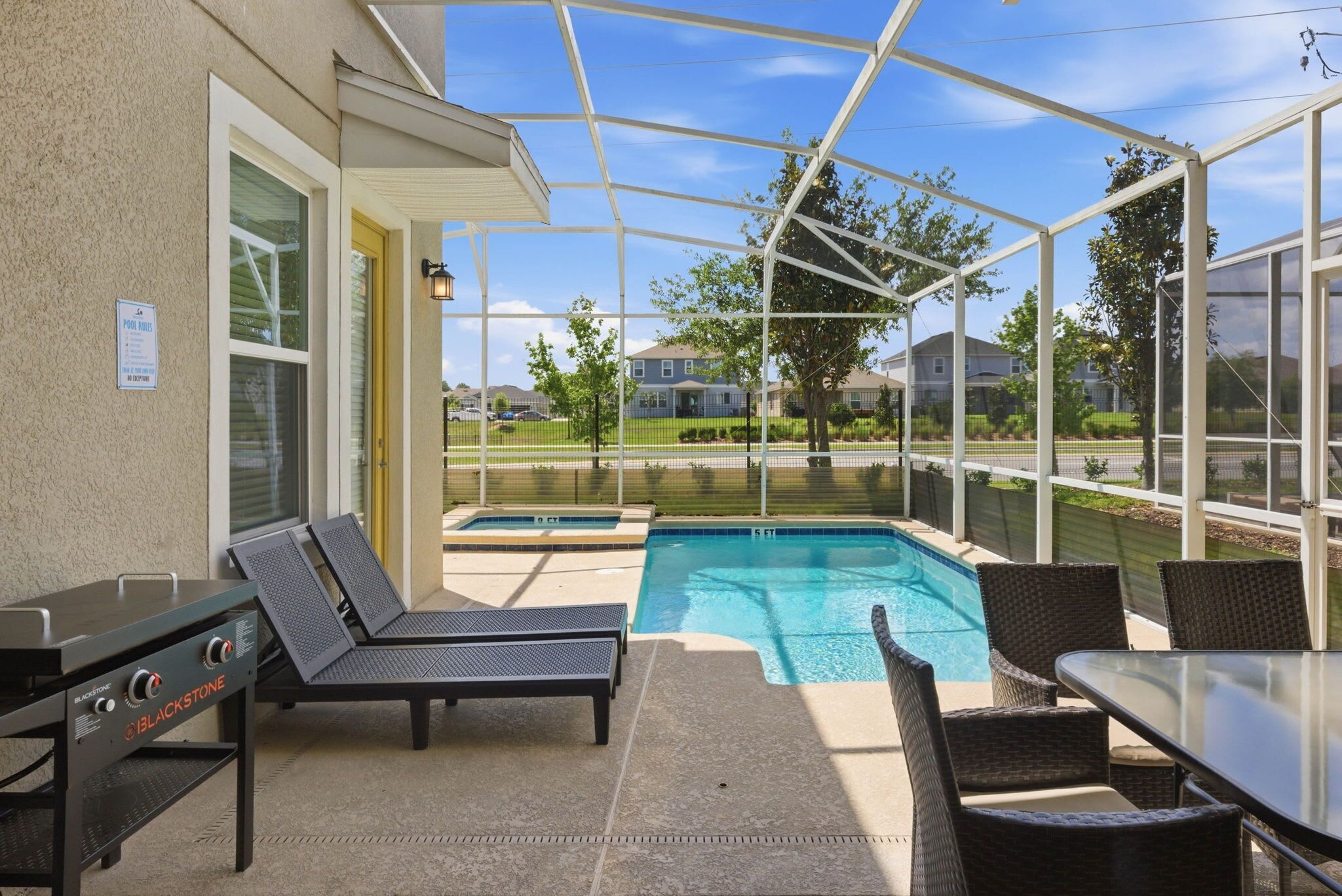 Un espace extérieur avec une piscine, des chaises longues, une table et un barbecue.
