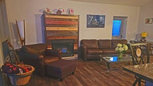 A living room with a fireplace, leather sofas, a coffee table, and a dining area. - Forested 3/BR-Bth, patio & Lanai, movie & billiards rms, chef's kitchen,close by (Bellevue)