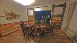 A dining area with a wooden table and chairs, a bench along the wall, and a view into another room. - Forested 3/BR-Bth, patio & Lanai, movie & billiards rms, chef's kitchen,close by (Bellevue)