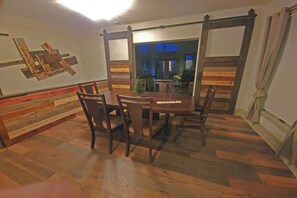 A dining area with a wooden table and chairs, a bench along the wall, and a view into another room. - Forested 3/BR-Bth, patio & Lanai, movie & billiards rms, chef's kitchen,close by (Bellevue)