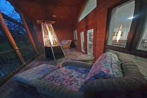 A cozy room with wicker furniture, a standing heater, and a window with a view. - Forested 3/BR-Bth, patio & Lanai, movie & billiards rms, chef's kitchen,close by (Bellevue)