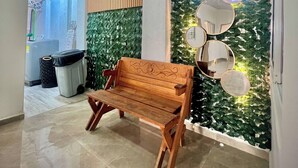 Um banco de madeira em um corredor com uma parede coberta de folhagem verde e uma lousa.