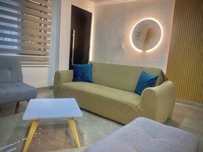 A modern living room with a sofa, a small table, and a wall-mounted circular light fixture. - House of Heaven Tourism Medical Salsa (Cali)