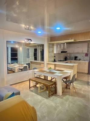 A modern kitchen with a dining area, a large window, and a built-in cabinet. - House of Heaven Tourism Medical Salsa (Cali)