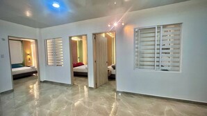 Um quarto espaçoso com piso polido, uma cama com travesseiro vermelho e uma janela com persianas.
