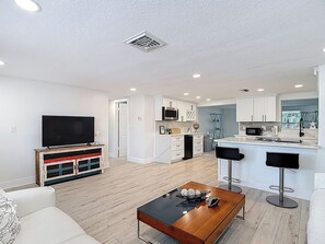 A modern apartment with a living room, kitchen, and dining area. - Gulf Breeze Retreat - Private 2BR/2BA  w/Fire Pit, Grill & Cozy Backyard. (New Port Richey)