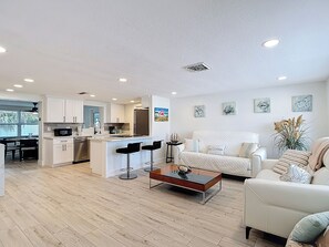 A modern living space with a kitchen, dining area, and seating area. - Gulf Breeze Retreat - Private 2BR/2BA  w/Fire Pit, Grill & Cozy Backyard. (New Port Richey)