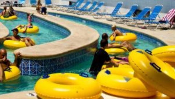 Une piscine avec des bouées gonflables jaunes, des chaises longues et un bâtiment en arrière-plan.