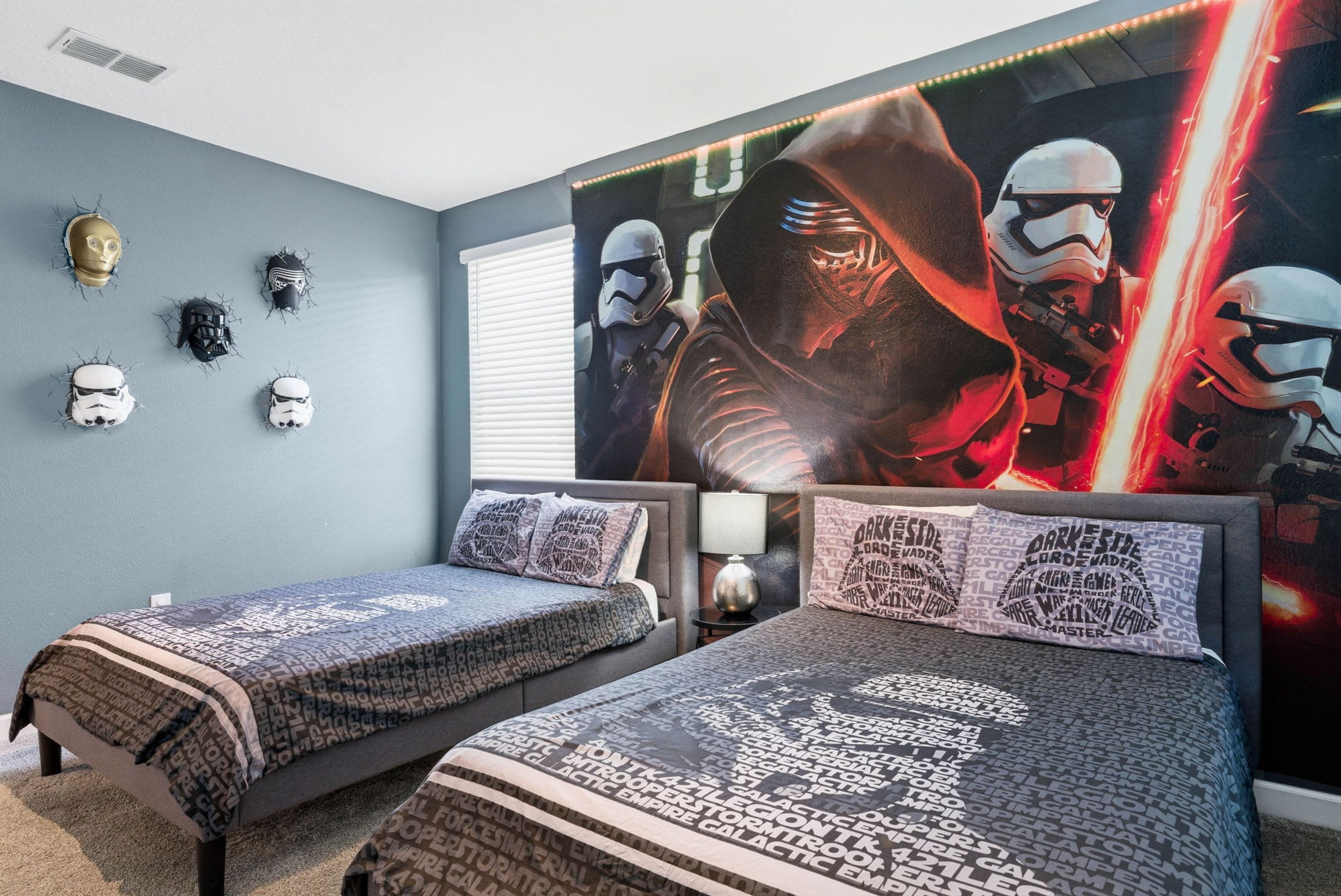 A bedroom with two beds, Star Wars themed decor, and a large poster on the wall.