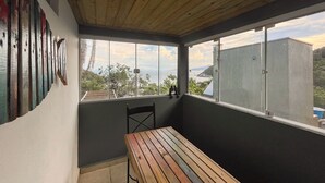 A balcony with a wooden table, a chair, and a view of the sea and hills. - At the top of Tainha beach, with a beautiful view that you can only find at Cabana do Abib. (Bombinhas)