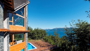 Un edificio moderno con fachada de piedra, terraza de madera y piscina.