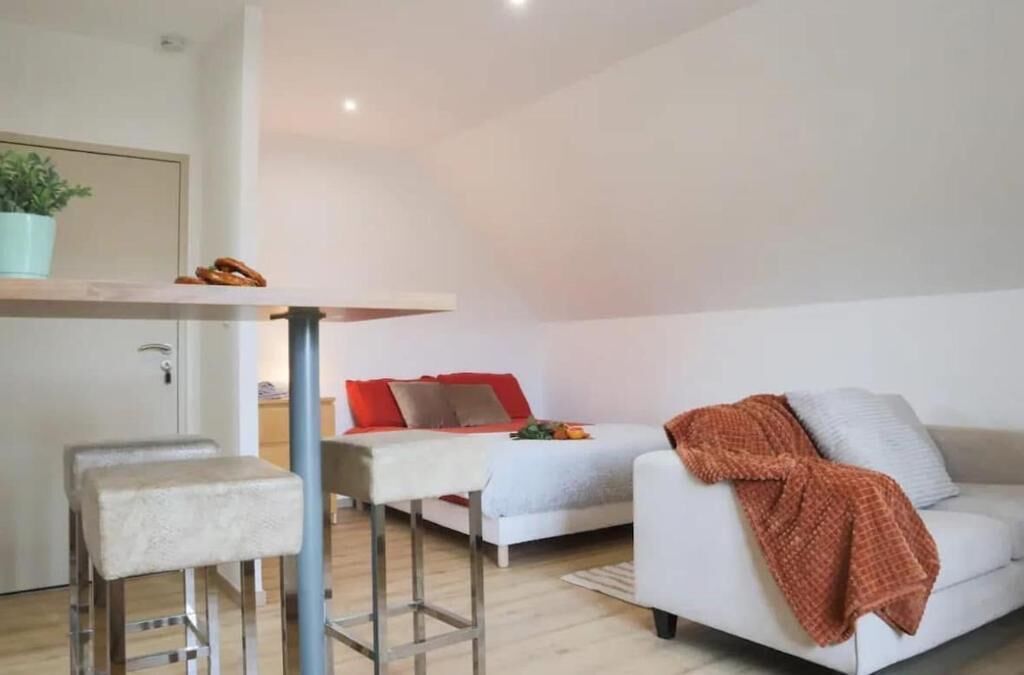 Ein moderner Wohnbereich mit Sofa, Essbereich und kleiner Küche.