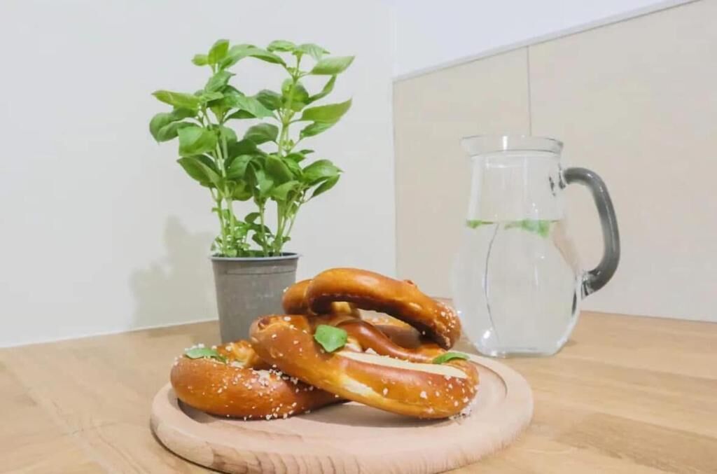 A wooden table with pretzels and a clear glass pitcher.