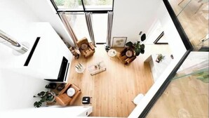 Un intérieur moderne avec un plancher en bois, un canapé, une table basse et une petite plante.