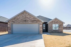 A residential house with a garage, a small attached structure, and a clear sky. - The Carlisle - 3BR/2BA - Family Friendly New Build (Lubbock)