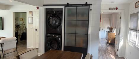 Una cocina moderna con una isla central, electrodomésticos integrados y una zona de comedor con mesa y sillas de madera.