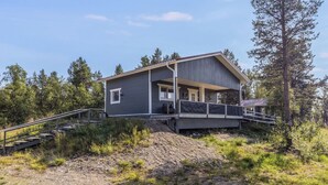 A modern house with a covered porch, a staircase leading up to it, and a forested backdrop. - Sevettijärventie 8753 by Interhome (Inari)