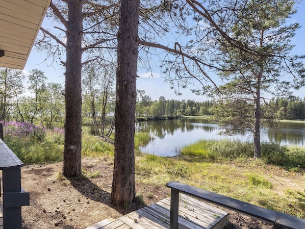 A lakeside view with trees and a wooden deck.