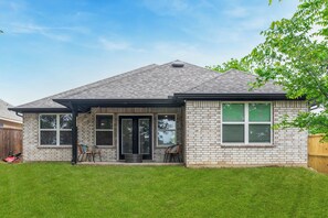 A single-story house with a brick exterior, a covered patio, and a fenced yard. - Hidden Lake Gem Arcade Stay (Denison)