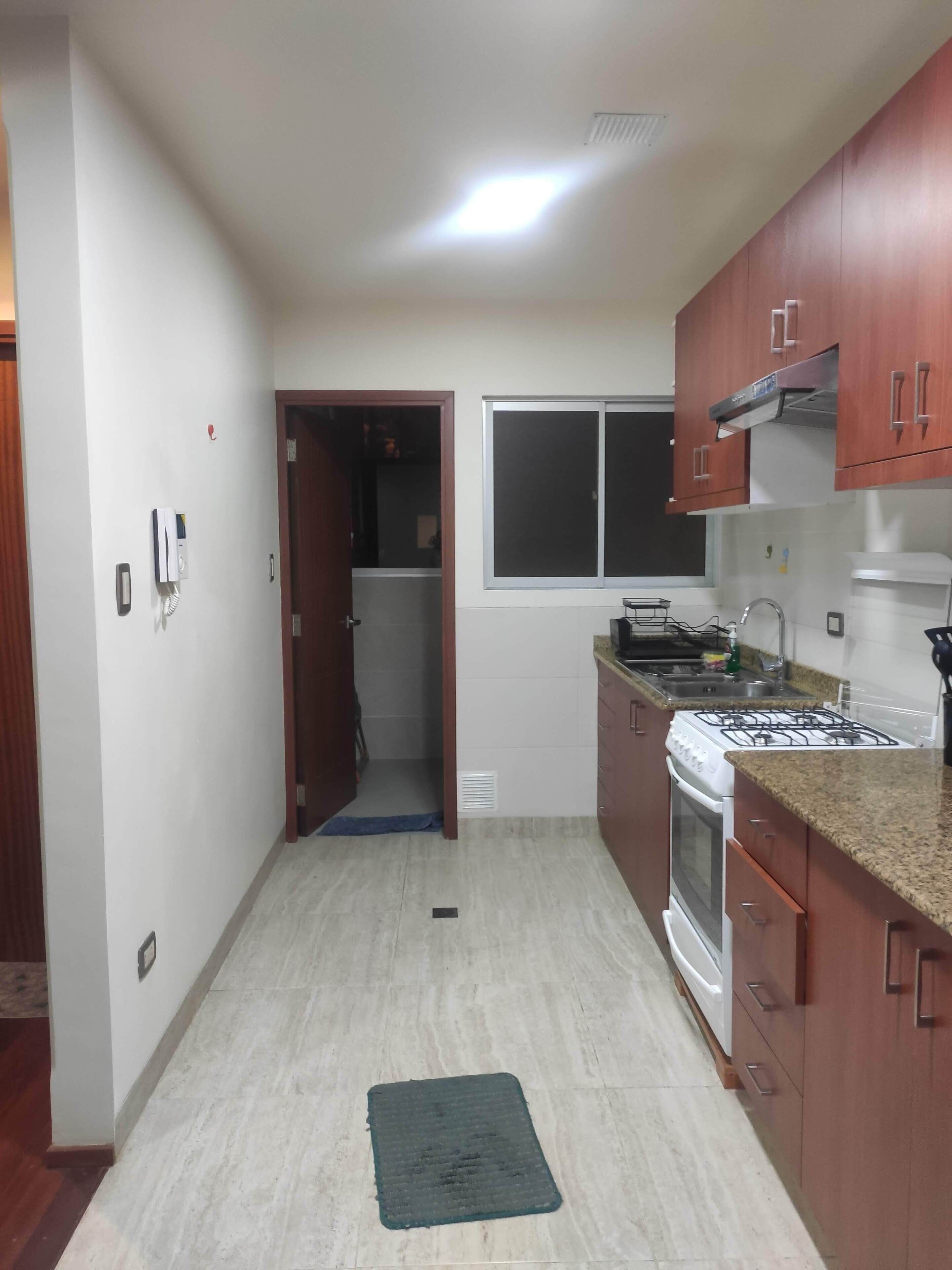 A kitchen with a stove, sink, and cabinets.