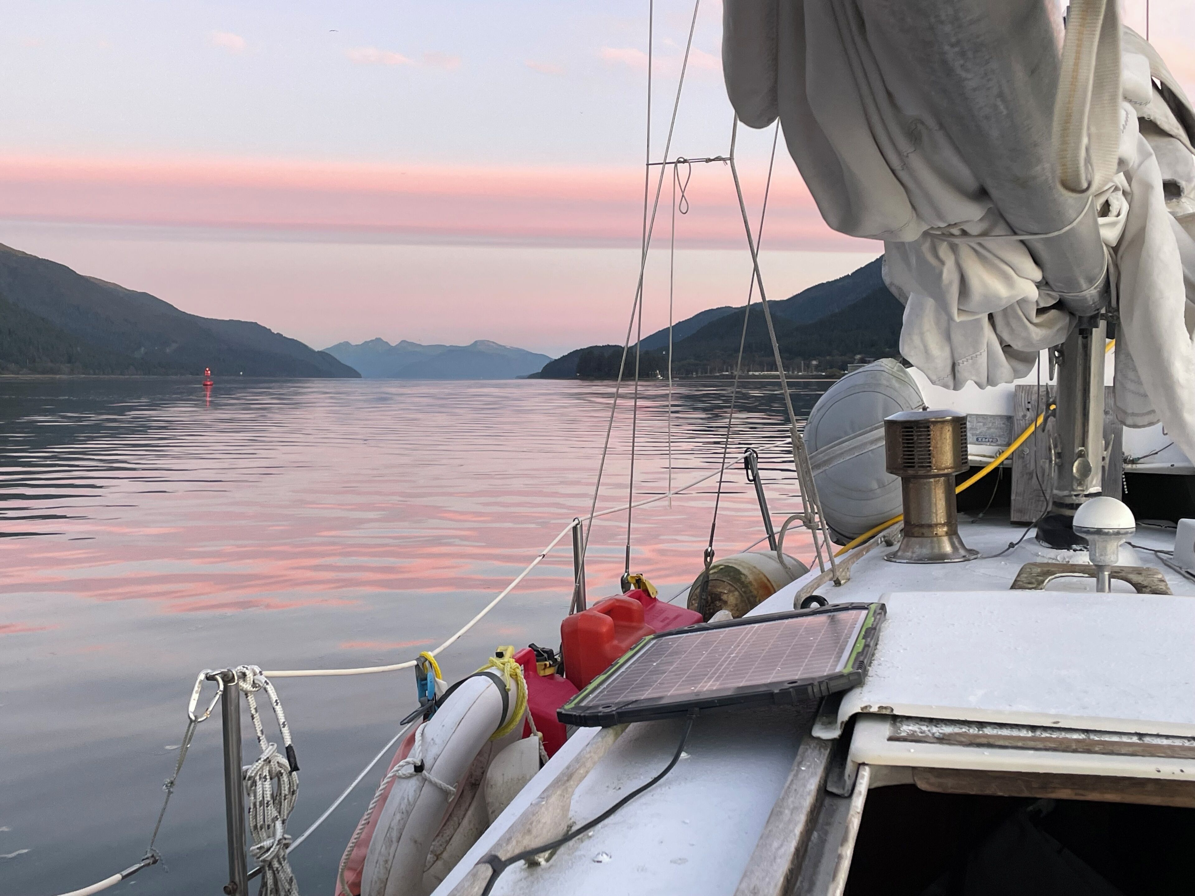 A boat with a mast, ropes, and a solar panel.