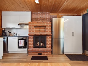 Una cocina moderna con chimenea de ladrillo, electrodomésticos de acero inoxidable y techo de madera.