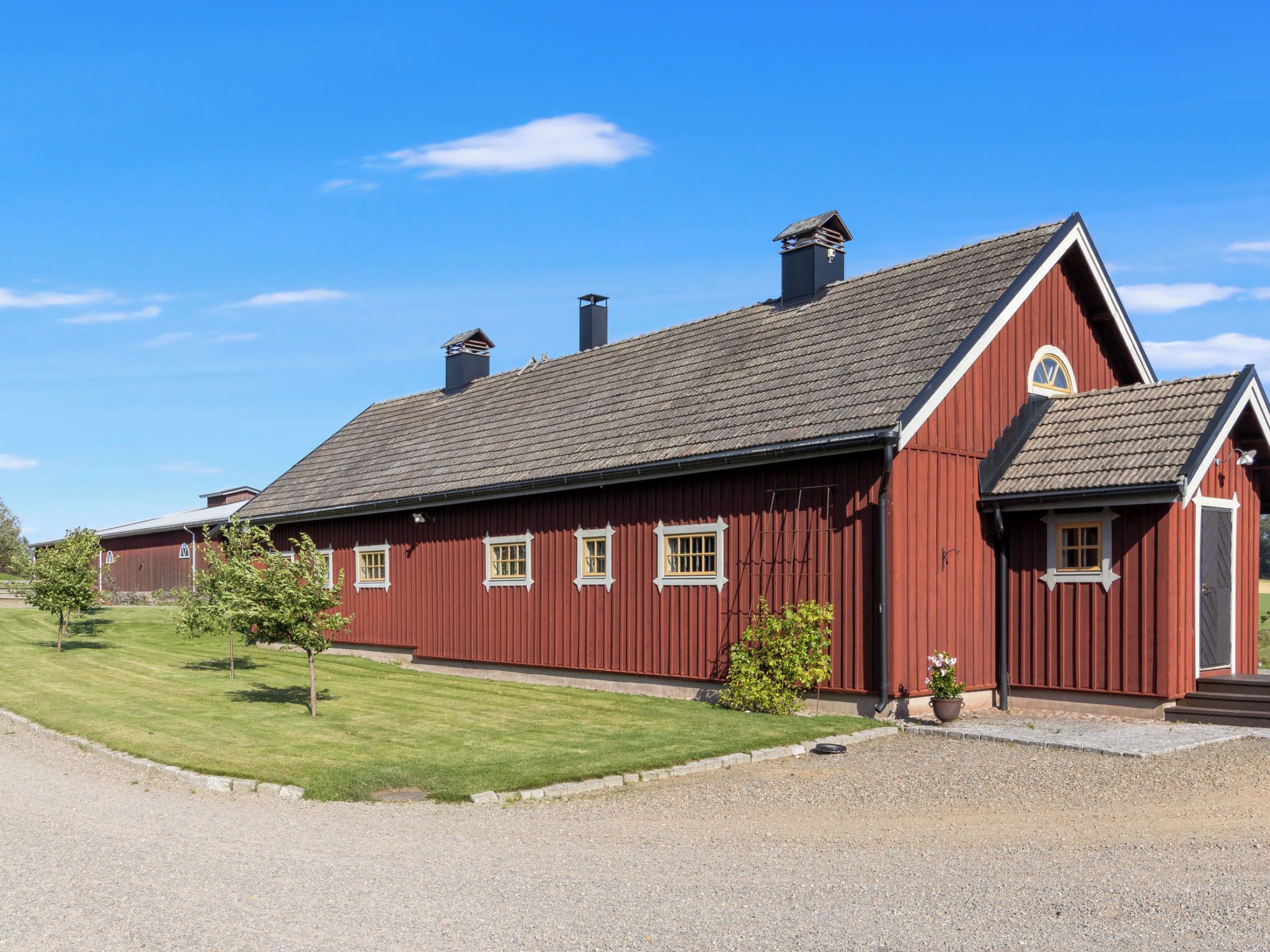 A red barn-style building with a sloped roof, multiple chimneys, and a small porch area.