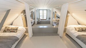 Une chambre avec deux lits, une grande fenêtre et un escalier menant à un étage supérieur.