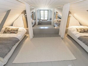 Une chambre avec deux lits, une grande fenêtre et un escalier menant à un étage supérieur.