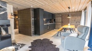 A modern kitchen with dark cabinetry, a wooden dining table, and a leather sofa.