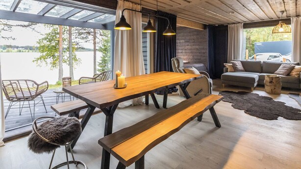 A wooden interior with a dining table, benches, and a sofa.