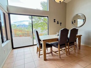 Ein Essbereich mit Tisch und Stühlen, eine Schiebetür zum Balkon und ein wandmontierter Spiegel.