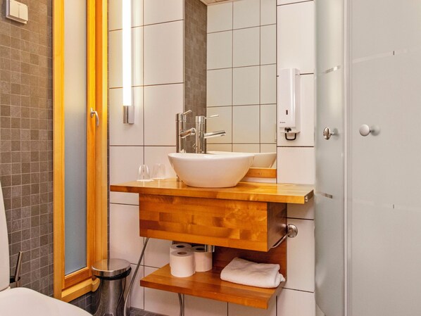 A bathroom with a wooden vanity, a white sink, a mirror, and a towel rack.