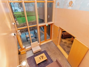 A modern interior with large windows, a wooden deck, and a seating area with a table.