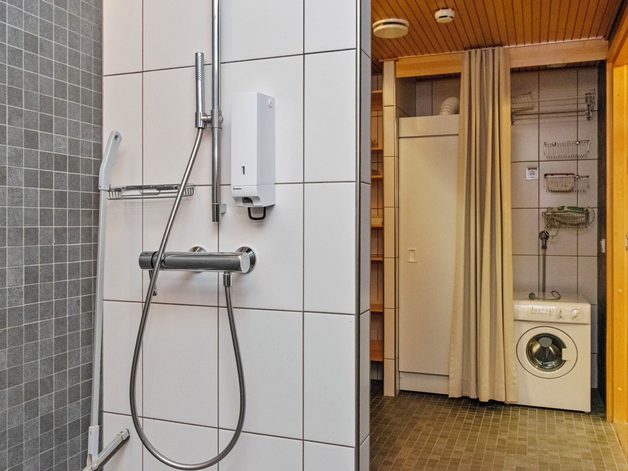 Un baño con ducha, inodoro y lavadora.