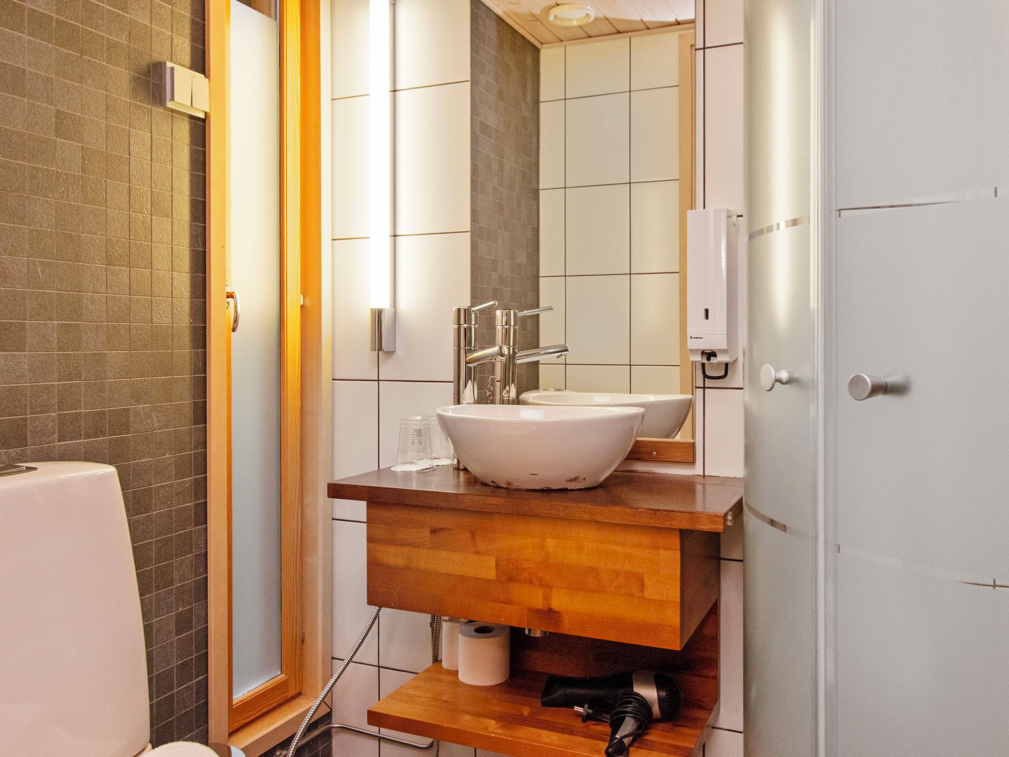 Une salle de bain avec un lavabo blanc, un meuble-lavabo en bois et un miroir.