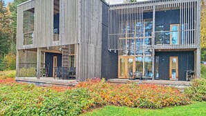 A modern two-story building with a wooden exterior, large windows, and a deck area. - Villa sinikka 1 by Interhome (Mikkeli)