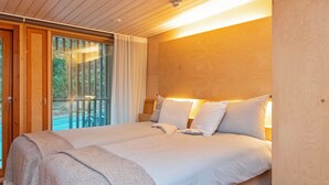 A bedroom with a large bed, a balcony with curtains, and a wooden ceiling. - Villa sinikka 1 by Interhome (Mikkeli)