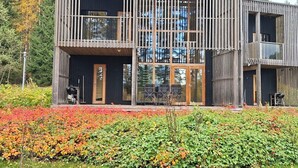 A modern two-story building with large windows, a balcony, and a well-maintained garden with colorful foliage. - Villa sinikka 2 by Interhome (Mikkeli)