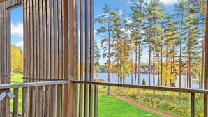 A wooden deck with a view of a lake and trees. - Villa sinikka 2 by Interhome (Mikkeli)