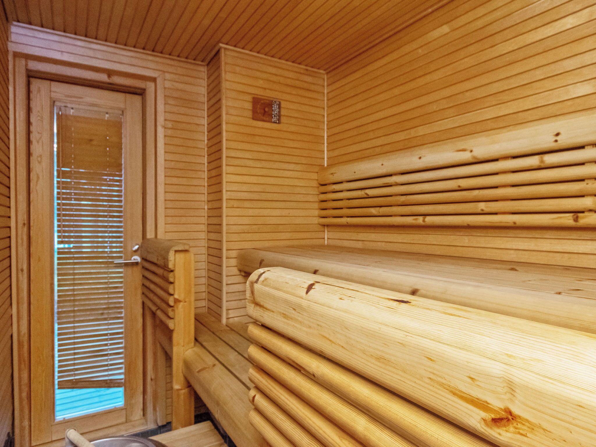 Ein Saunaraum mit Holzbänken und einer Tür mit Jalousien.