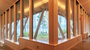 Un intérieur moderne avec des poutres en bois, de grandes fenêtres et une vue sur un lac.