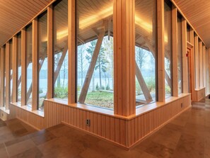 Un interior moderno con vigas de madera, ventanas amplias y vistas a un lago.
