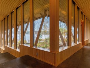 A wooden interior with large windows, a tiled floor, and a view of a lake.