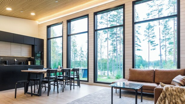 Un intérieur moderne comprenant une cuisine, un coin repas et un espace détente avec de grandes fenêtres donnant sur une forêt.