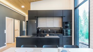 Une cuisine moderne dotée d’un îlot central, d’appareils électroménagers intégrés et d’une grande fenêtre offrant une vue sur l’extérieur.