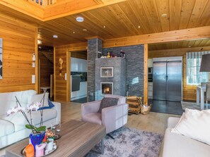 Ein modernes Blockhaus-Interieur mit Wohnzimmer, Küche und Kamin.