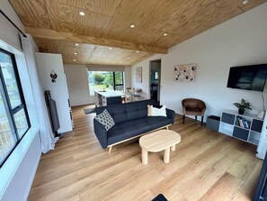 A modern living room with a sofa, coffee table, and TV stand. - Beautiful lake front home (Queenstown)
