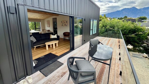 Un bâtiment moderne doté d’un balcon, de planchers en bois et offrant une vue sur les montagnes.