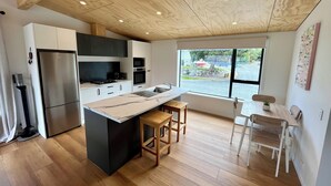 Une cuisine moderne dotée d’un îlot central, de planchers en bois et offrant une vue sur la rue.